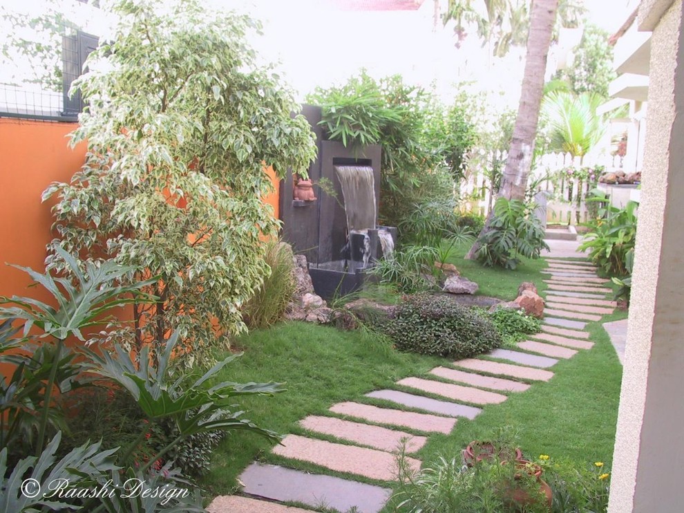 This is an example of a mid-sized tropical backyard garden in San Francisco with a water feature and natural stone pavers.