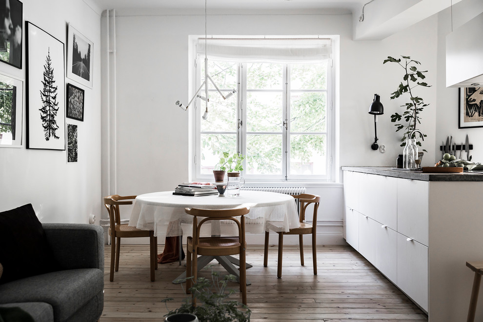 Immagine di una sala da pranzo aperta verso il soggiorno nordica di medie dimensioni con pareti bianche, parquet chiaro e pavimento beige