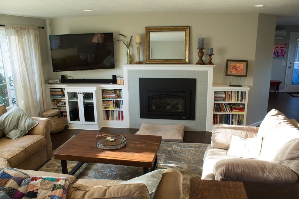 Mid-sized transitional open concept living room in Other with dark hardwood floors, brown floor, beige walls, a standard fireplace, a tile fireplace surround, a library and a wall-mounted tv.
