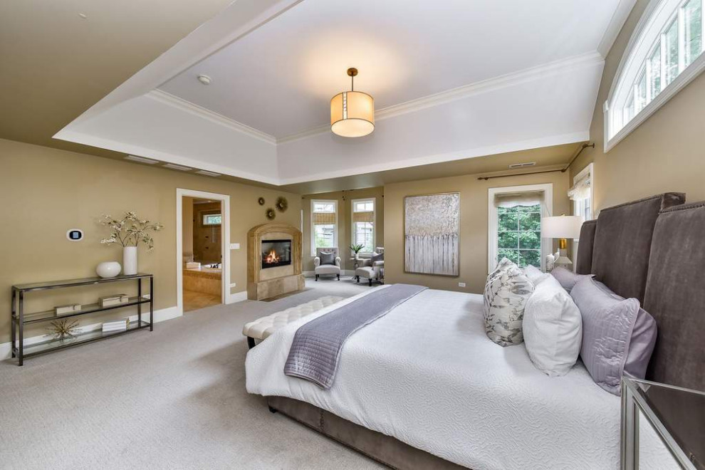 Inspiration for a large transitional master bedroom in Chicago with beige walls, carpet, a standard fireplace, a tile fireplace surround, white floor and vaulted.