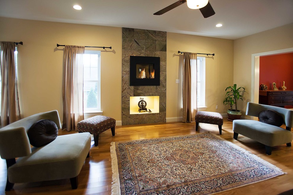 Photo of a large eclectic formal enclosed living room in St Louis with beige walls, light hardwood floors, a standard fireplace, a tile fireplace surround and no tv.