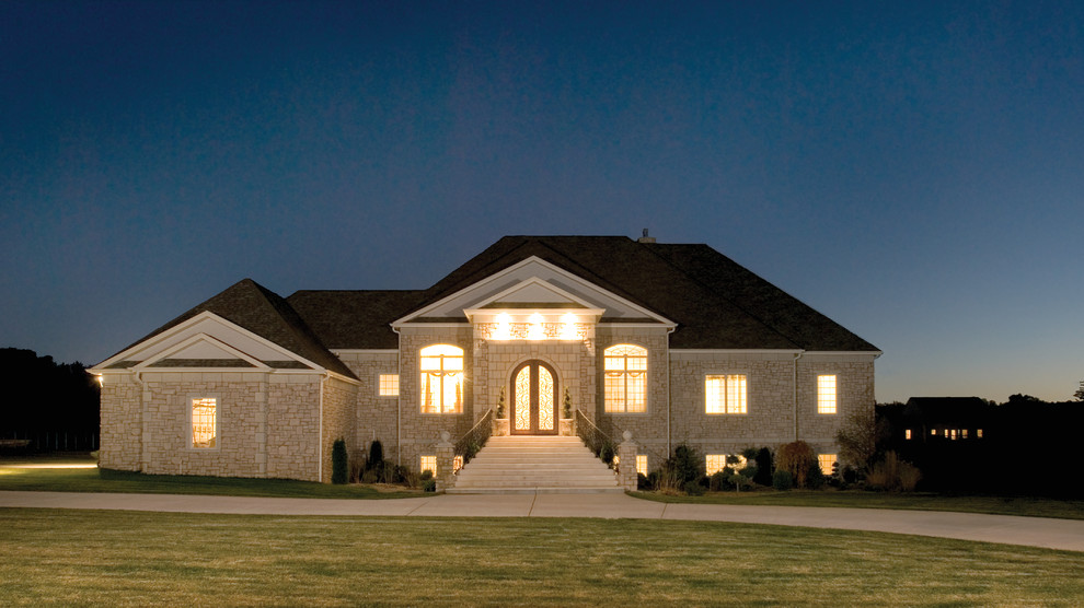 Photo of an expansive traditional two-storey beige exterior in Other with stone veneer.