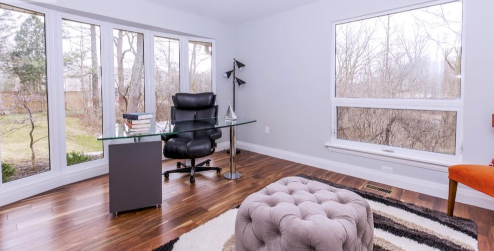 This is an example of a mid-sized contemporary study room in Toronto with grey walls, dark hardwood floors, no fireplace and a freestanding desk.
