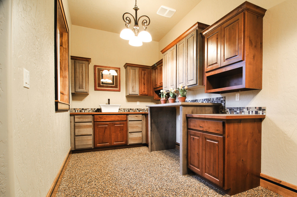 This is an example of a large country l-shaped utility room in Seattle with raised-panel cabinets, dark wood cabinets, laminate benchtops, beige walls, concrete floors and a side-by-side washer and dryer.