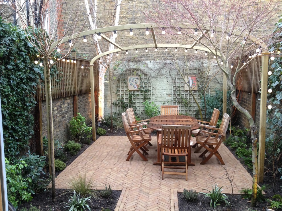 Mid-sized traditional backyard patio in London with a vertical garden and brick pavers.