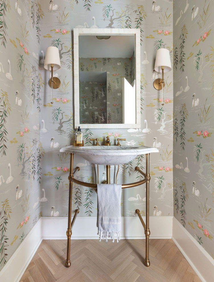 Photo of a traditional powder room in New York with multi-coloured walls, light hardwood floors, a console sink and beige floor.
