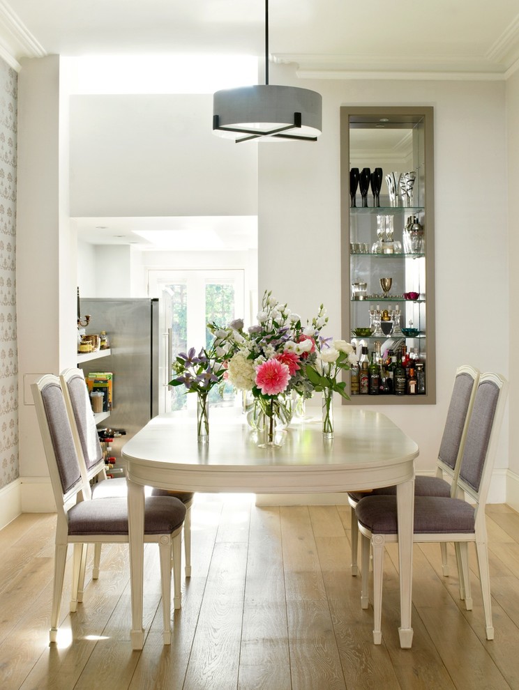 Design ideas for a transitional dining room in London with white walls and light hardwood floors.