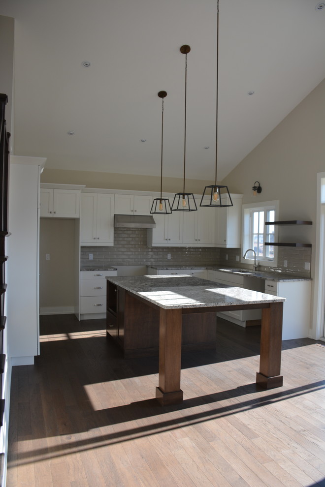 Eat-in kitchen - mid-sized transitional u-shaped light wood floor and brown floor eat-in kitchen idea in Toronto with shaker cabinets, white cabinets, granite countertops, gray backsplash, subway tile backsplash, an island, a double-bowl sink and stainless steel appliances
