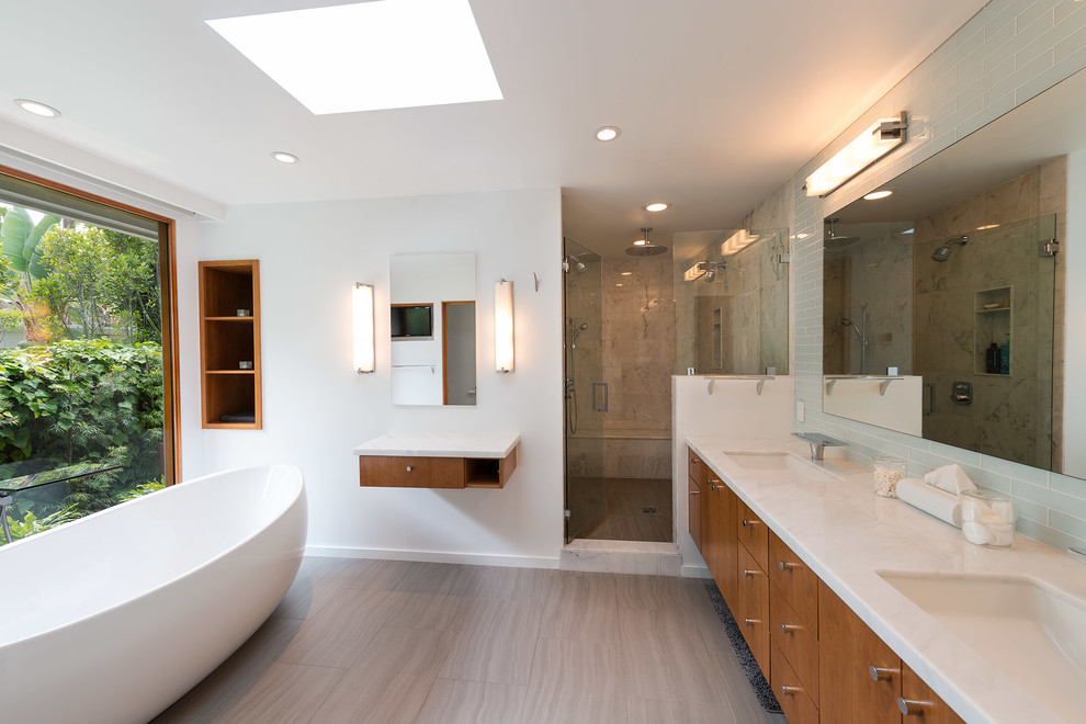 Large modern master bathroom in Los Angeles with a freestanding tub, flat-panel cabinets, dark wood cabinets, an alcove shower, gray tile, marble, white walls, porcelain floors, an undermount sink, marble benchtops, brown floor, a hinged shower door and white benchtops.