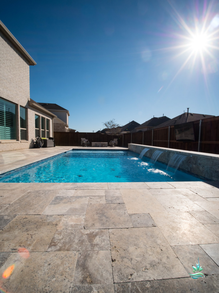 Ejemplo de piscina alargada moderna de tamaño medio rectangular en patio lateral con paisajismo de piscina y adoquines de piedra natural