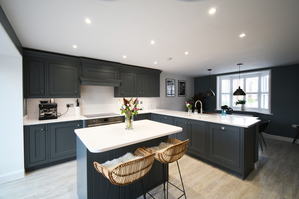 Photo of a large traditional grey and white l-shaped kitchen/diner in Essex with a single-bowl sink, shaker cabinets, grey cabinets, quartz worktops, black appliances, an island and white worktops.