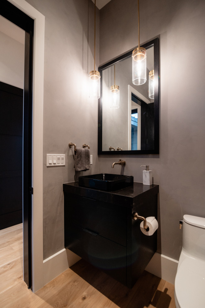 Réalisation d'un petit WC et toilettes design avec un placard à porte plane, des portes de placard noires, un carrelage gris, un mur gris, parquet clair, une vasque, un plan de toilette en quartz, un sol beige, un plan de toilette noir et meuble-lavabo suspendu.