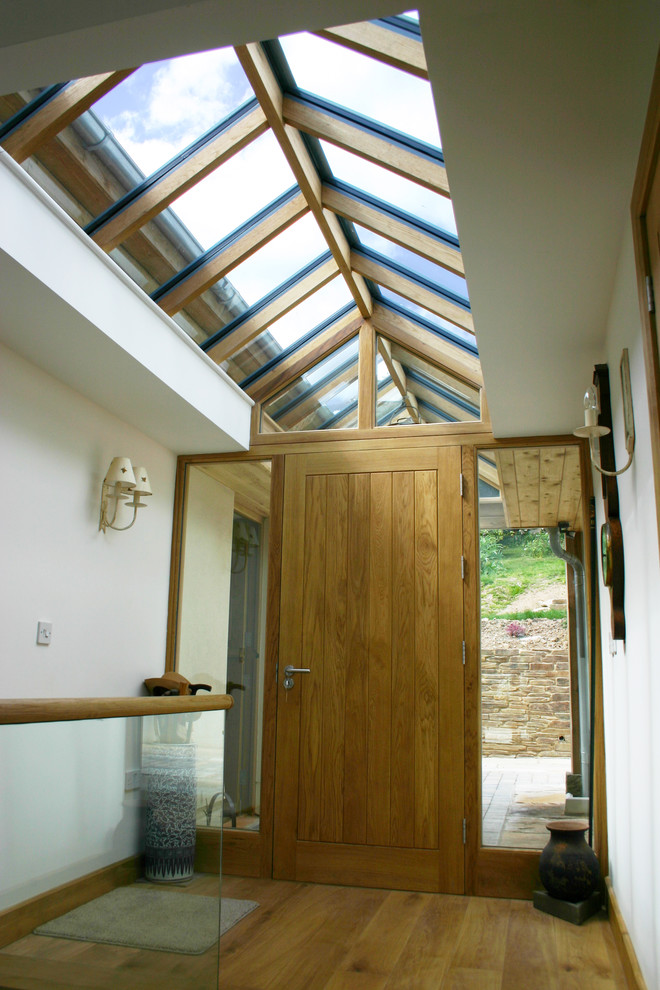 This is an example of a large traditional entry hall in Devon with white walls, medium hardwood floors, a single front door and a medium wood front door.