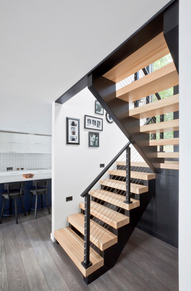 This is an example of a mid-sized modern wood u-shaped staircase in Indianapolis with open risers and cable railing.