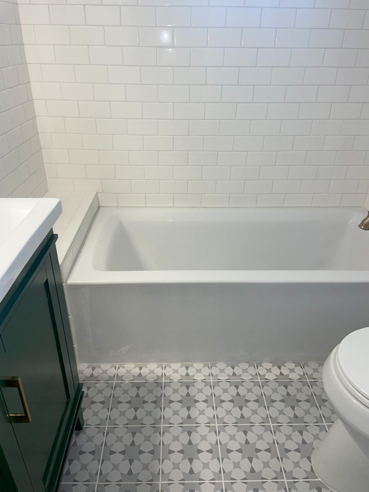 Inredning av ett litet vit vitt badrum för barn, med en dusch/badkar-kombination, en toalettstol med separat cisternkåpa, vit kakel, tunnelbanekakel, grått golv, skåp i shakerstil, gröna skåp, ett platsbyggt badkar, vita väggar, klinkergolv i porslin, ett integrerad handfat, bänkskiva i kvarts och dusch med duschdraperi