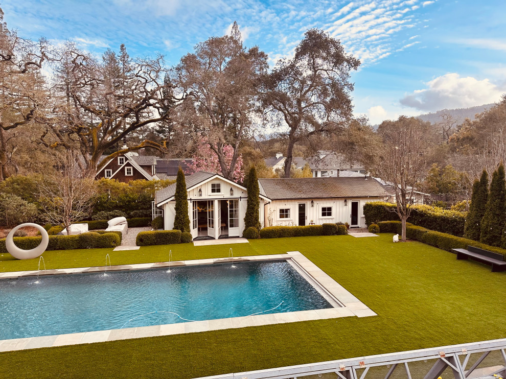 Foto de piscina natural clásica grande rectangular en patio trasero con paisajismo de piscina y adoquines de piedra natural