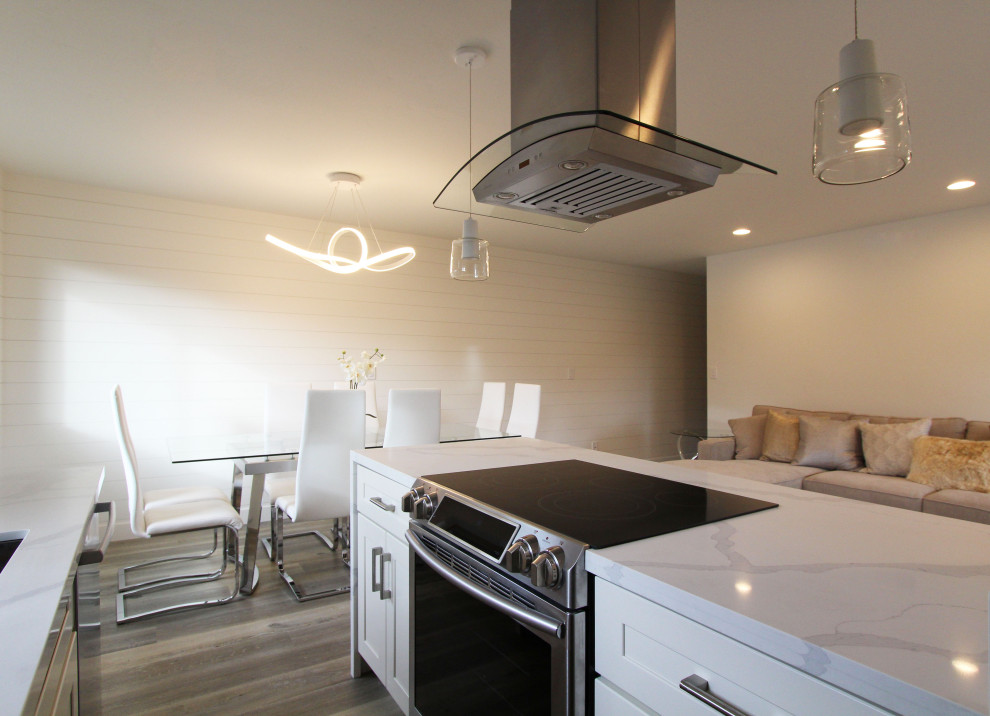 Open concept kitchen - small galley vinyl floor and brown floor open concept kitchen idea with an undermount sink, shaker cabinets, white cabinets, quartz countertops, white backsplash, quartz backsplash, stainless steel appliances, a peninsula and white countertops