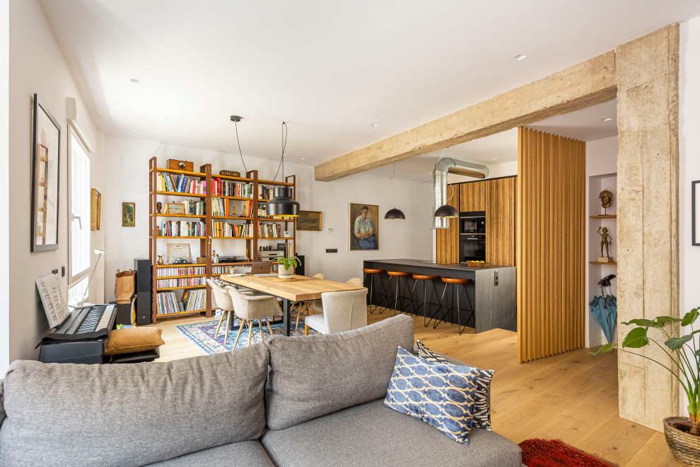 Imagen de salón abierto industrial con paredes blancas, suelo de madera en tonos medios y suelo marrón