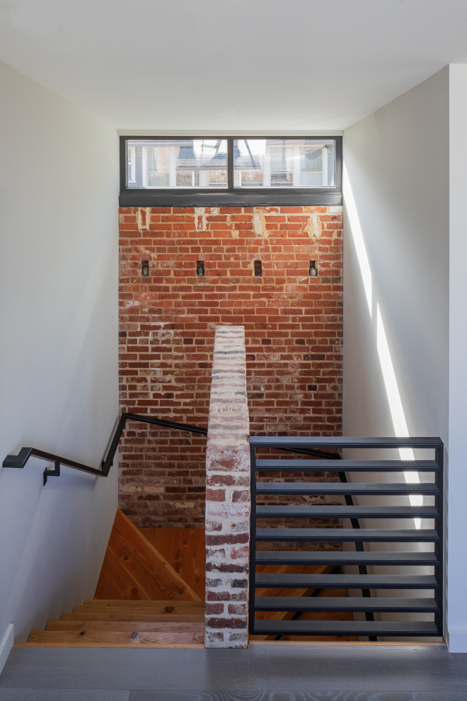 Modelo de escalera industrial sin contrahuella con escalones de madera, barandilla de metal y ladrillo