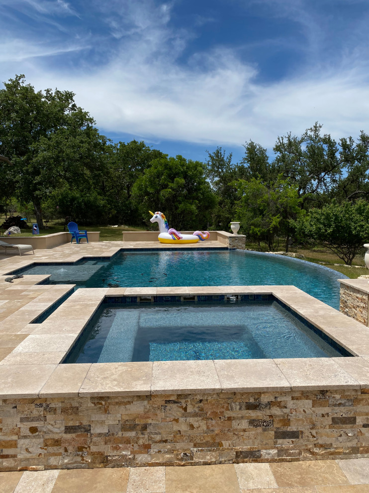 Photo of an expansive modern backyard custom-shaped infinity pool in Austin with with privacy feature and decking.