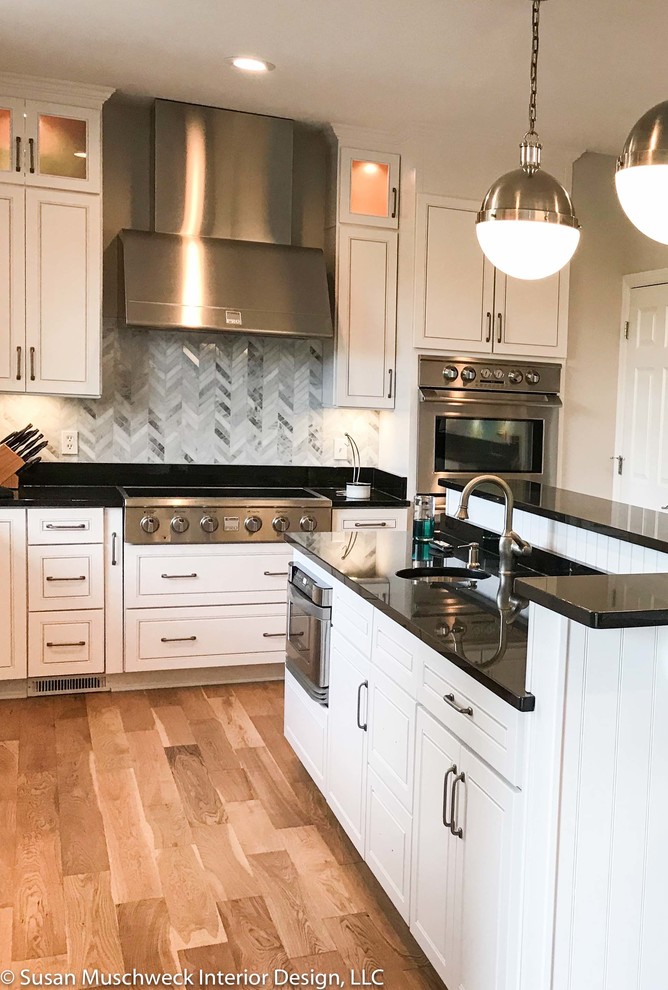 Open concept kitchen - large transitional light wood floor open concept kitchen idea with an undermount sink, raised-panel cabinets, white cabinets, granite countertops, multicolored backsplash, marble backsplash, stainless steel appliances, an island and black countertops