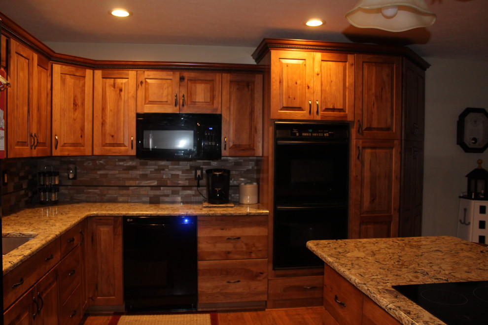 Open concept kitchen - large rustic l-shaped medium tone wood floor and brown floor open concept kitchen idea with an undermount sink, raised-panel cabinets, brown cabinets, quartzite countertops, metallic backsplash, black appliances, an island and brown countertops