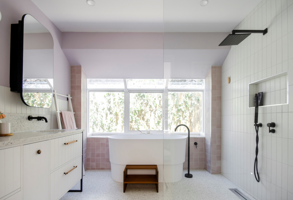 メルボルンにある高級な広いコンテンポラリースタイルのおしゃれな浴室 (白いキャビネット、洗面台2つ、インセット扉のキャビネット、置き型浴槽、オープン型シャワー、ビデ、ピンクのタイル、セメントタイル、ピンクの壁、テラゾーの床、オーバーカウンターシンク、テラゾーの洗面台、白い床、オープンシャワー、白い洗面カウンター、アクセントウォール、独立型洗面台、白い天井) の写真