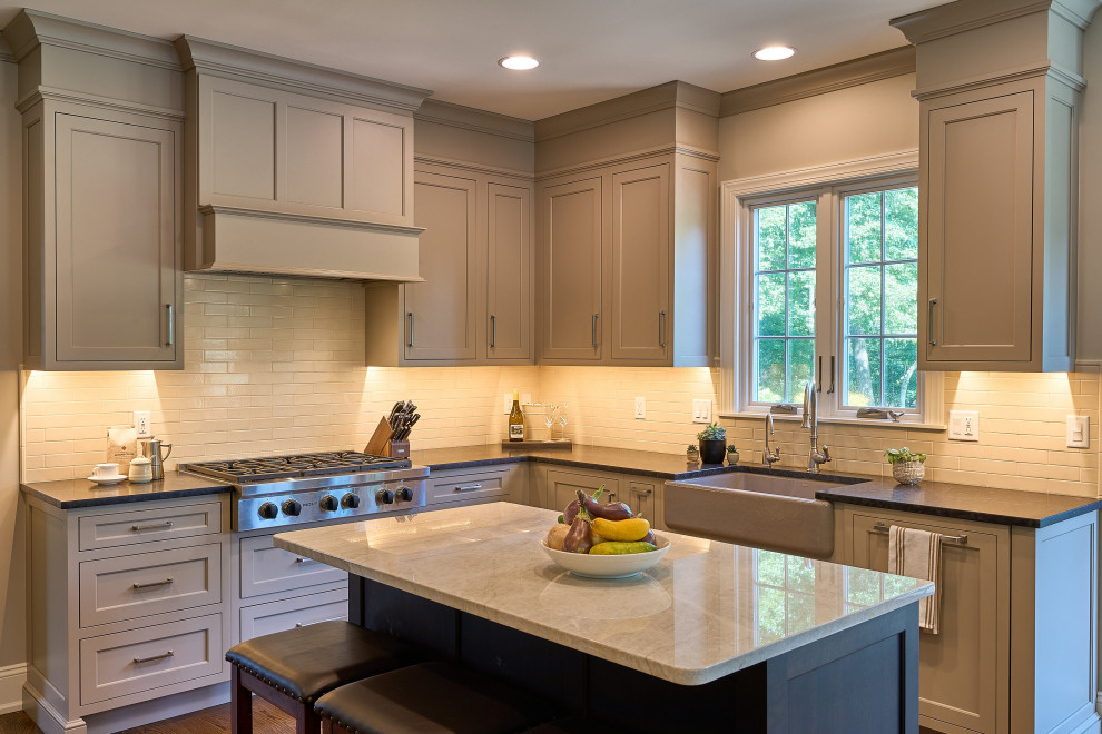 This is an example of a large modern u-shaped eat-in kitchen in Philadelphia with a farmhouse sink, beige cabinets, granite benchtops, beige splashback, subway tile splashback, stainless steel appliances, medium hardwood floors, with island, brown floor and brown benchtop.