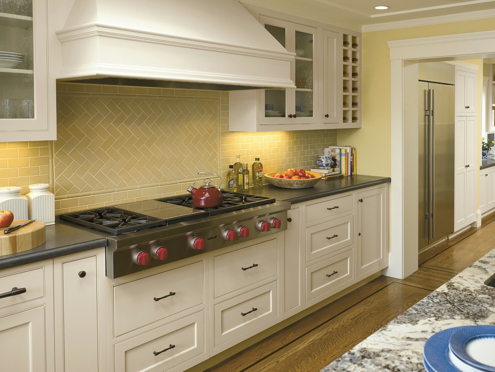 Example of a mid-sized classic l-shaped light wood floor eat-in kitchen design in Toronto with an undermount sink, shaker cabinets, white cabinets, granite countertops, yellow backsplash, ceramic backsplash, stainless steel appliances and an island