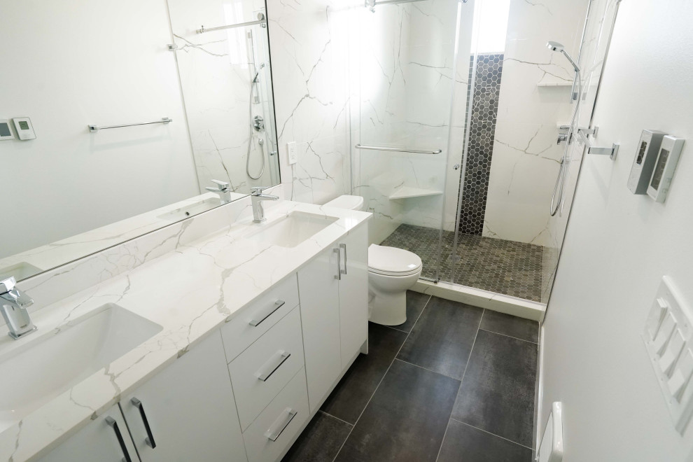 シアトルにある高級な中くらいなコンテンポラリースタイルのおしゃれなバスルーム (浴槽なし) (白いキャビネット、一体型トイレ	、白いタイル、大理石タイル、白い壁、珪岩の洗面台、引戸のシャワー、白い洗面カウンター、洗面台2つ、独立型洗面台、クッションフロア、茶色い床、白い天井) の写真