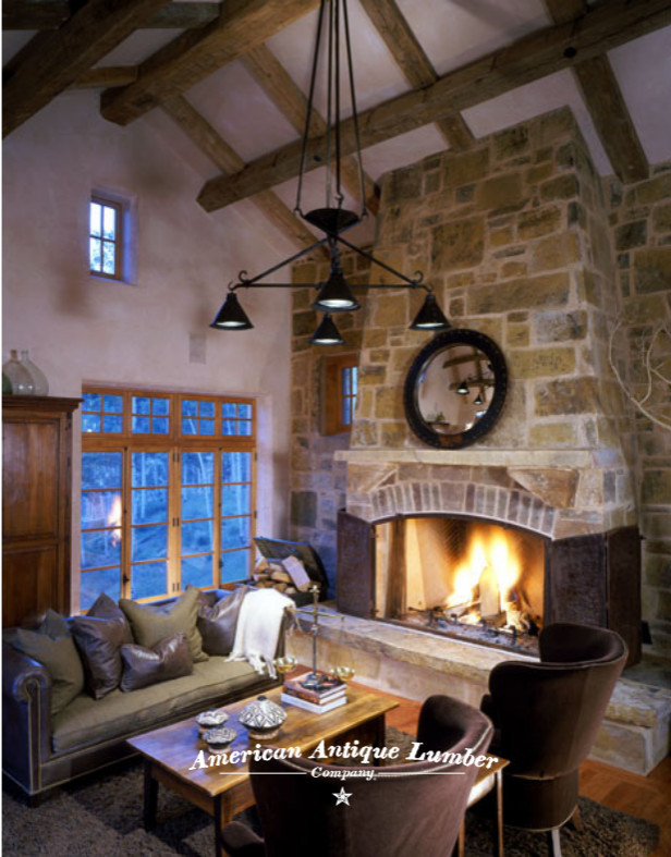This is an example of a mid-sized country enclosed living room with a library, white walls, medium hardwood floors, a standard fireplace, a stone fireplace surround, no tv, multi-coloured floor and exposed beam.