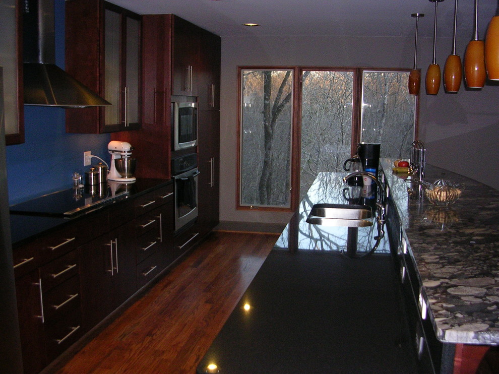 Example of a large mountain style galley medium tone wood floor eat-in kitchen design in Birmingham with an undermount sink, glass-front cabinets, dark wood cabinets, granite countertops, stainless steel appliances, blue walls and an island