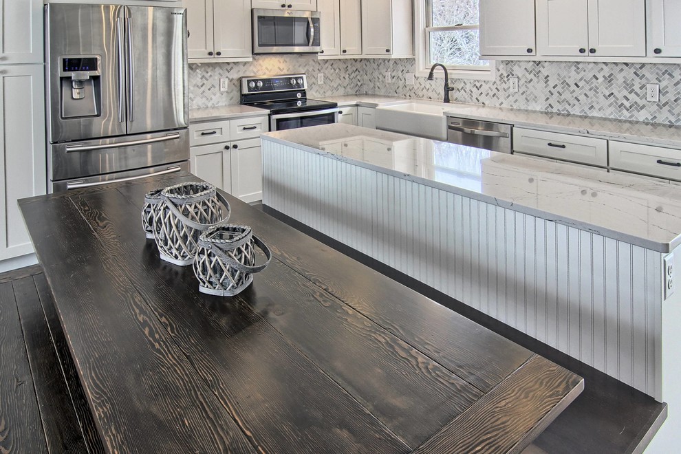 Eat-in kitchen - mid-sized transitional l-shaped vinyl floor eat-in kitchen idea with a farmhouse sink, shaker cabinets, white cabinets, quartz countertops, white backsplash, stone tile backsplash, stainless steel appliances and an island