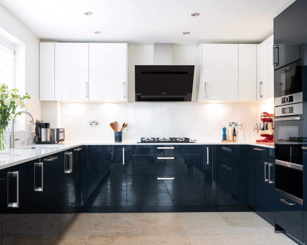 This is an example of a mid-sized contemporary u-shaped eat-in kitchen in Berkshire with flat-panel cabinets, blue cabinets, quartzite benchtops, black appliances, no island and white benchtop.