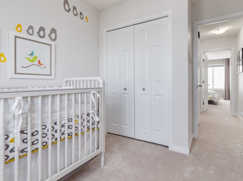 Modelo de habitación de bebé actual de tamaño medio con paredes grises, moqueta y suelo beige