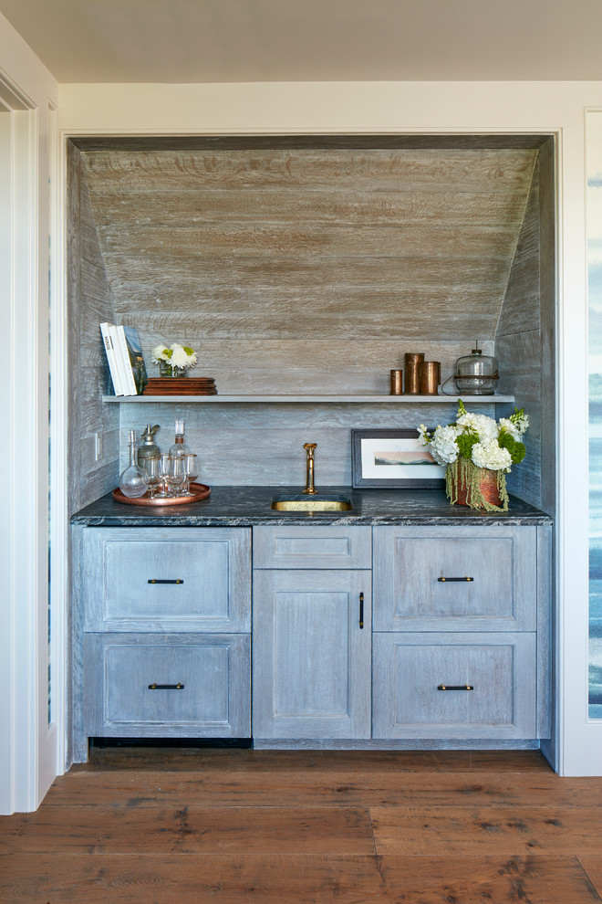 This is an example of a small beach style single-wall wet bar in Charleston with an undermount sink, shaker cabinets, distressed cabinets, timber splashback, multi-coloured benchtop and medium hardwood floors.