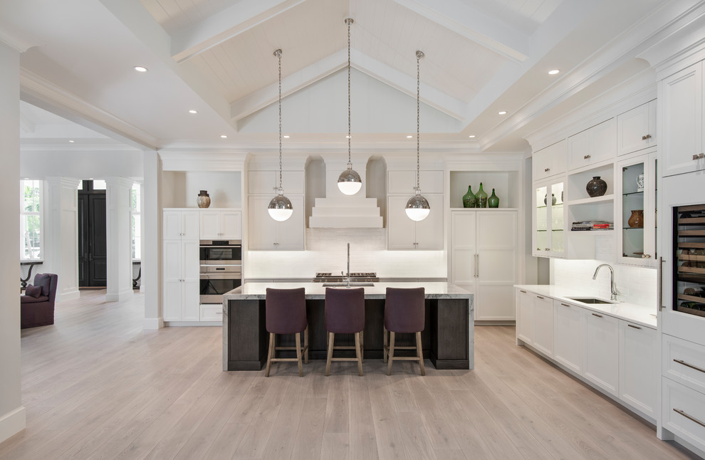Example of a transitional light wood floor open concept kitchen design with stainless steel appliances and an island