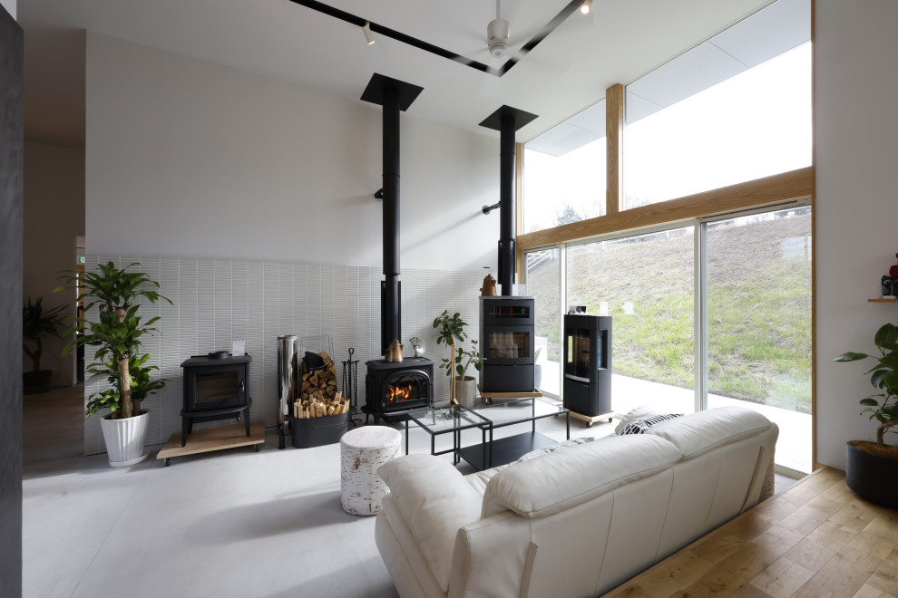 Idée de décoration pour un salon nordique avec un poêle à bois, un manteau de cheminée en carrelage, un sol gris et du lambris de bois.
