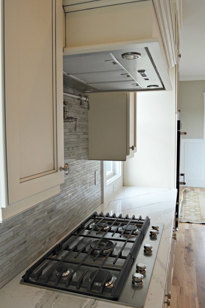 Light wood floor kitchen photo with a farmhouse sink, stainless steel appliances and an island