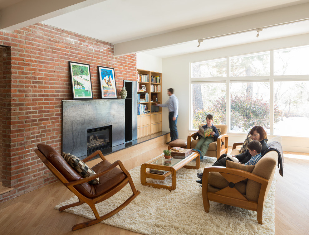 Design ideas for a midcentury enclosed living room in Denver with a library, white walls, light hardwood floors, a standard fireplace, a metal fireplace surround and no tv.