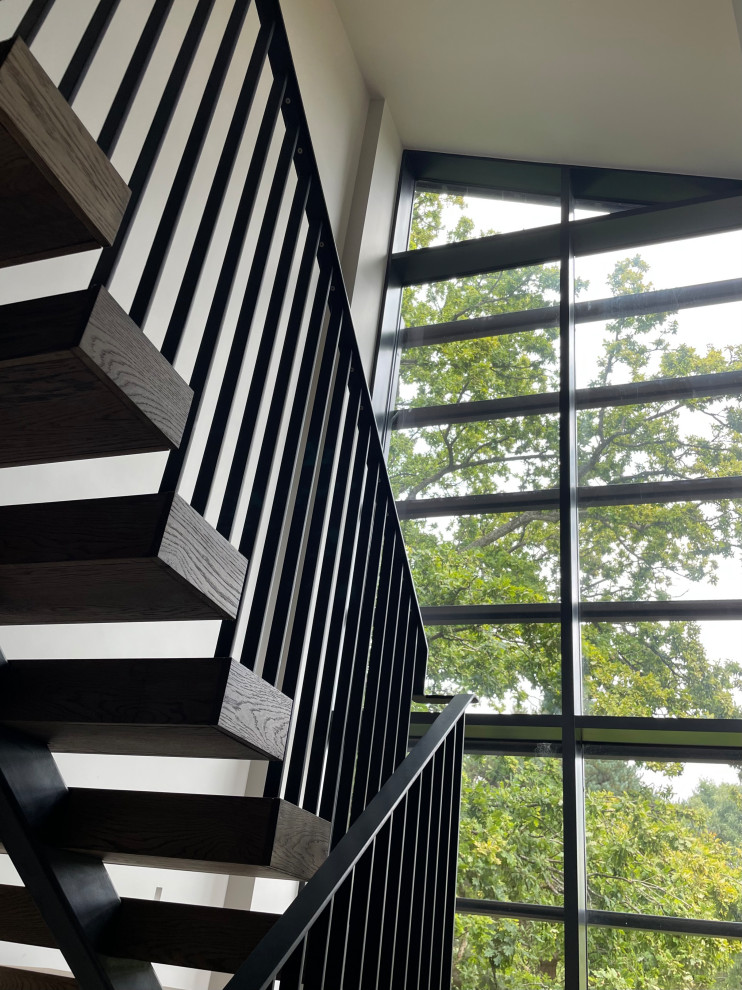 Идея дизайна: большая лестница на больцах в современном стиле с деревянными ступенями и металлическими перилами без подступенок