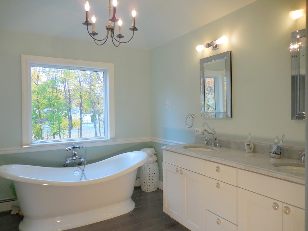Inspiration for a mid-sized traditional master bathroom in New York with recessed-panel cabinets, white cabinets, a freestanding tub, blue walls, an undermount sink and brown floor.