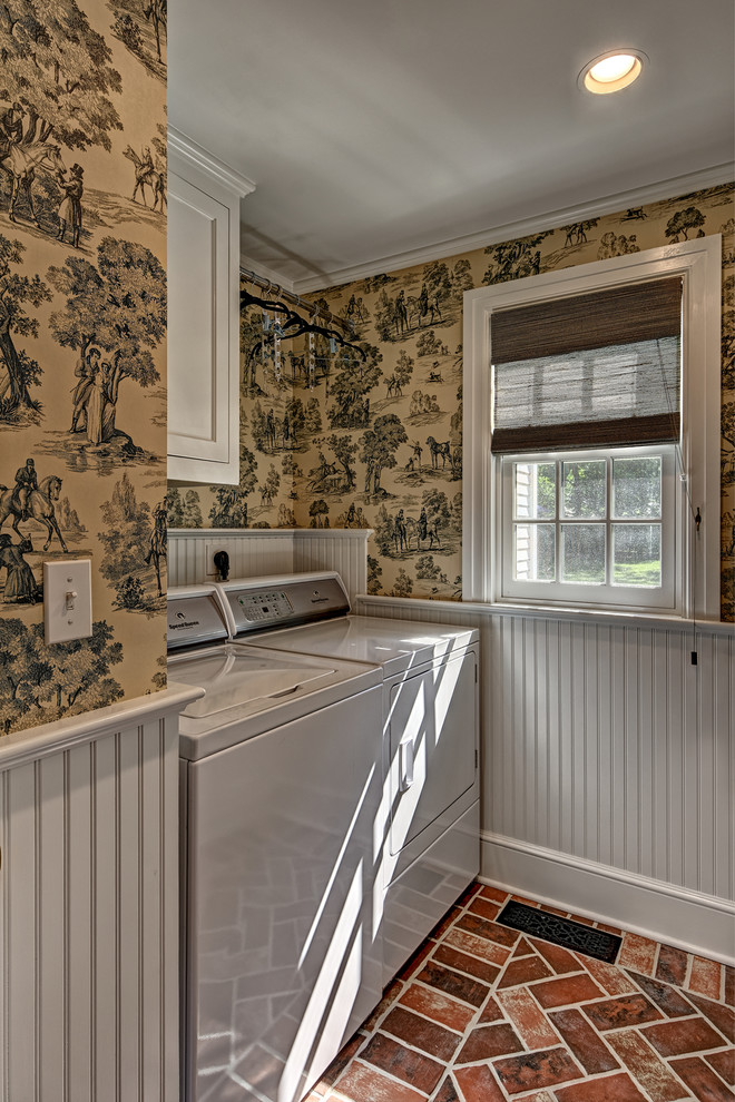 Inspiration for a mid-sized traditional single-wall utility room in New York with shaker cabinets, white cabinets, beige walls, brick floors, a side-by-side washer and dryer and brown floor.
