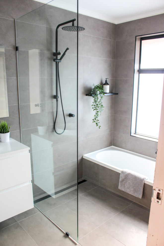 Design ideas for a mid-sized modern kids wet room bathroom in Perth with flat-panel cabinets, white cabinets, a drop-in tub, a one-piece toilet, gray tile, porcelain tile, grey walls, porcelain floors, a vessel sink, engineered quartz benchtops, grey floor, an open shower, white benchtops, a single vanity and a floating vanity.