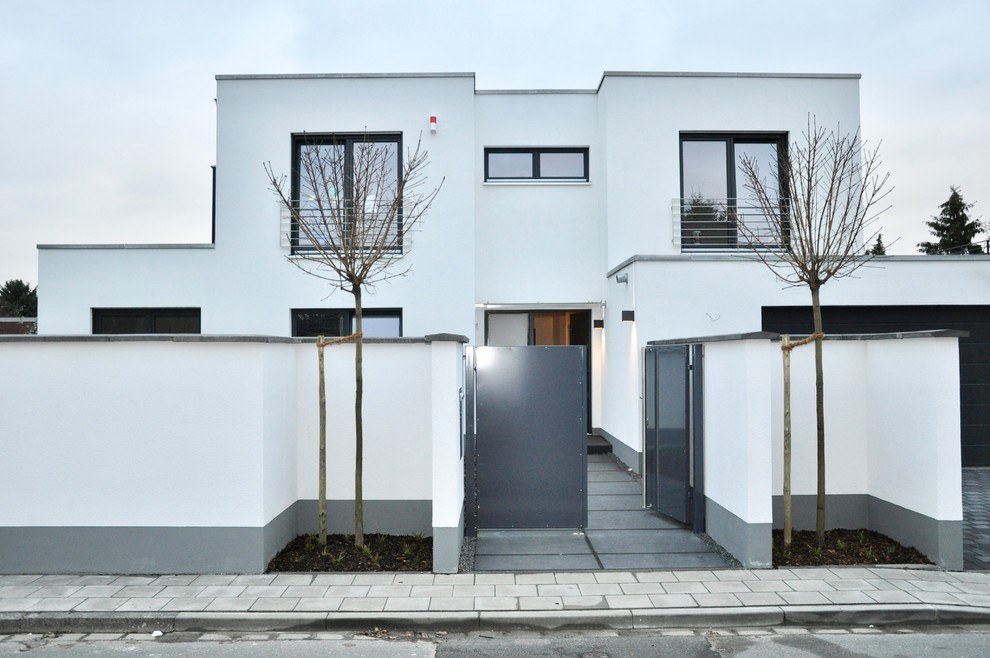 Mid-sized modern two-storey stucco white house exterior in Dusseldorf with a flat roof and a green roof.