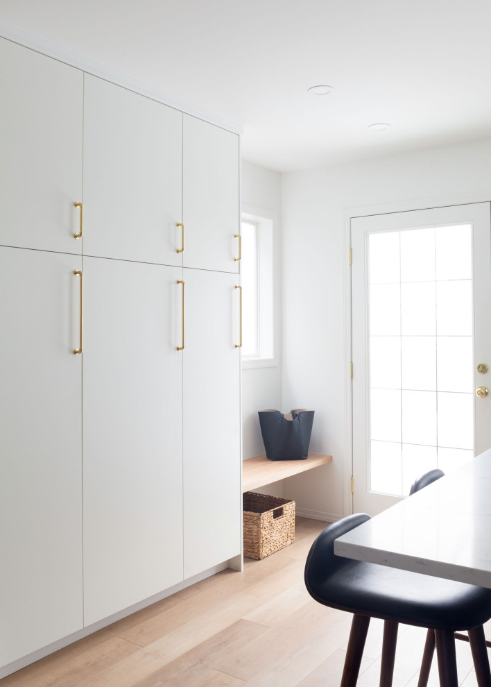 Example of a mid-sized transitional l-shaped light wood floor and brown floor open concept kitchen design in Calgary with an undermount sink, shaker cabinets, black cabinets, quartz countertops, white backsplash, porcelain backsplash, stainless steel appliances, an island and white countertops