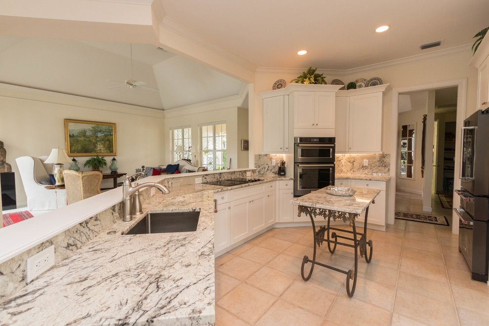 Eat-in kitchen - large transitional porcelain tile eat-in kitchen idea in Miami with an undermount sink, shaker cabinets, white cabinets, granite countertops, gray backsplash, stone slab backsplash, black appliances and an island