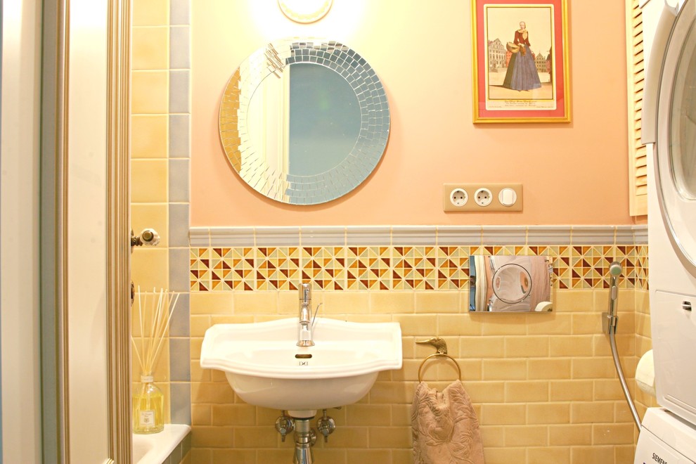 This is an example of a small traditional powder room in Moscow with a wall-mount toilet, beige tile, ceramic tile, pink walls and a wall-mount sink.