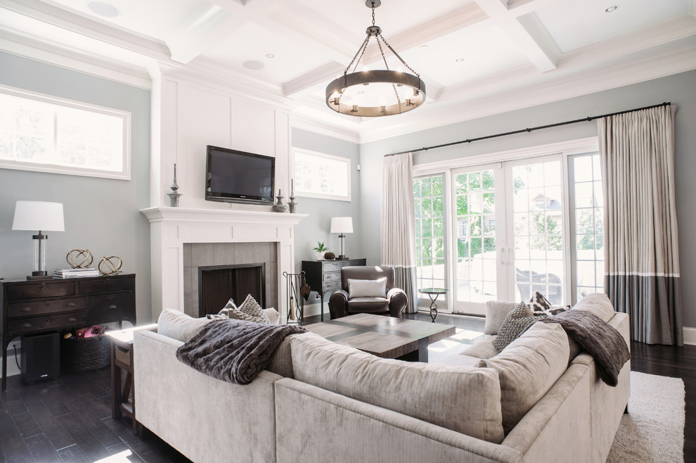 Design ideas for a large transitional open concept family room in Chicago with dark hardwood floors, a standard fireplace, a tile fireplace surround, a wall-mounted tv and grey walls.