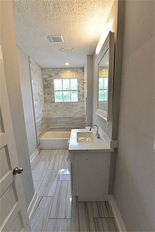 Design ideas for a mid-sized transitional 3/4 bathroom in Houston with shaker cabinets, white cabinets, an alcove tub, a shower/bathtub combo, a one-piece toilet, white tile, marble, grey walls, porcelain floors, an undermount sink, quartzite benchtops, grey floor and a shower curtain.